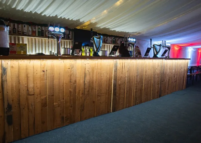Long wooden bar counter with drink taps inside the festive marquee